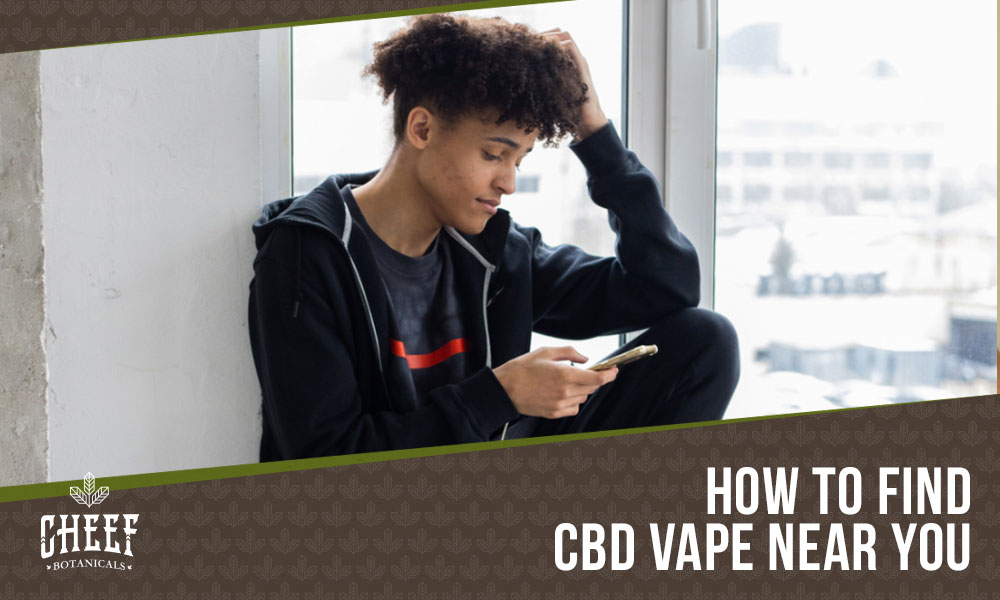 cbd vape near me (featured blog image by Cheef Botanicals) shows a young man using his phone by a window