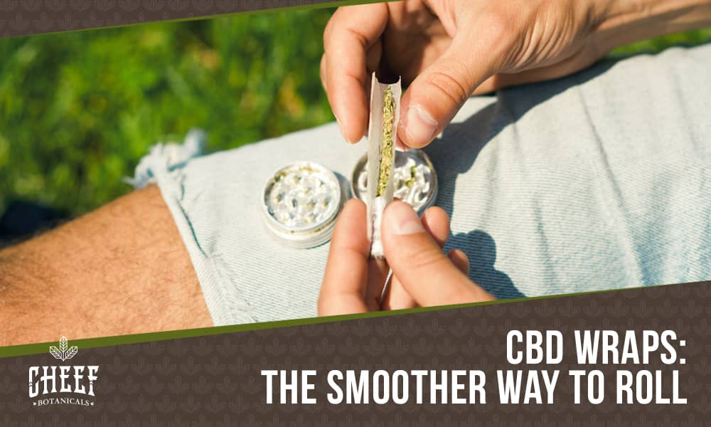 CBD Wraps featured blog image by Cheef Botanicals. Show a person's hands rolling a joint over a grinder that is balancing on their leg.